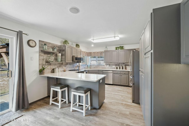 3206 N Lodgepole Rd, Coeur Dalene, ID 83815 - kitchen featuring stainless steel appliances, a peninsula, gray cabinetry, and decorative backsplash
