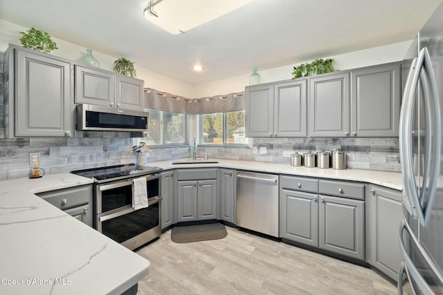 3206 N Lodgepole Rd, Coeur Dalene, ID 83815 - kitchen featuring gray cabinets, appliances with stainless steel finishes, decorative backsplash, and light wood finished floors