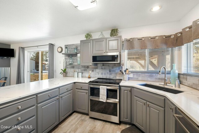 3206 N Lodgepole Rd, Coeur Dalene, ID 83815 - kitchen with gray cabinetry, appliances with stainless steel finishes, open shelves, decorative backsplash, and light wood-type flooring