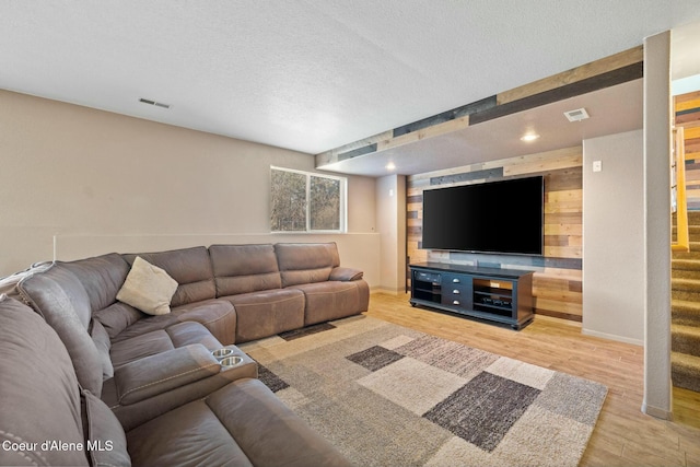 3206 N Lodgepole Rd, Coeur Dalene, ID 83815 - living room featuring stairs, light wood-style floors, a textured ceiling, and wood walls