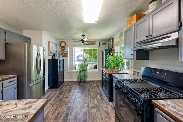 7315 W Lund St, Rathdrum, ID 83858 - kitchen with black range with gas cooktop, freestanding refrigerator, under cabinet range hood, ceiling fan, and dark wood-style flooring