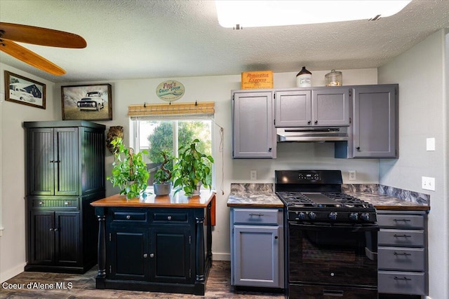 7315 W Lund St, Rathdrum, ID 83858 - kitchen with black gas range oven, under cabinet range hood, dark wood-type flooring, a ceiling fan, and a textured ceiling