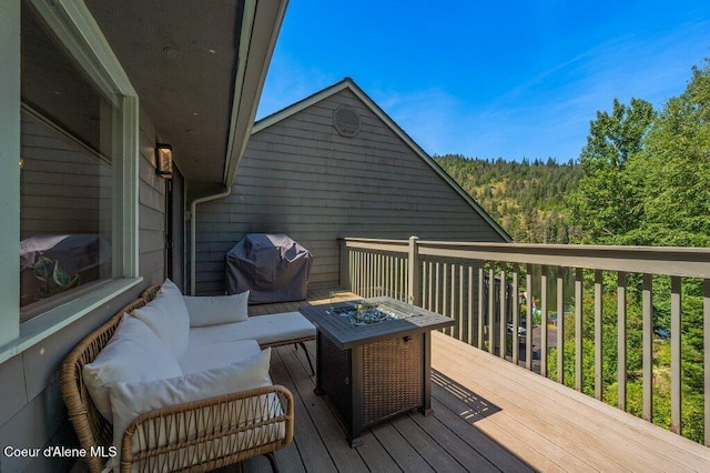 5653 W Racquet Rd, Rathdrum, ID 83858 - wooden terrace with area for grilling, a forest view, and an outdoor living space with a fire pit