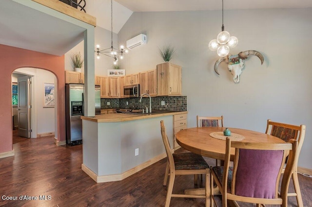 5653 W Racquet Rd, Rathdrum, ID 83858 - dining space with a chandelier, an AC wall unit, arched walkways, dark wood-style floors, and high vaulted ceiling