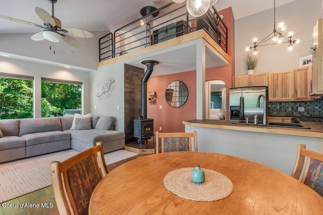 5653 W Racquet Rd, Rathdrum, ID 83858 - dining space with high vaulted ceiling, a ceiling fan, a wood stove, and wood finished floors