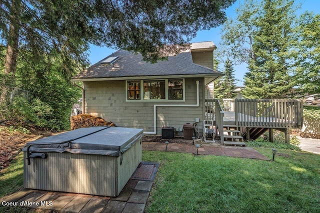 5653 W Racquet Rd, Rathdrum, ID 83858 - back of property with a hot tub, a wooden deck, roof with shingles, and a yard