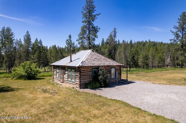 17320 E Perimeter Rd, Athol, ID 83801 - view of side of property with log exterior, a view of trees, a yard, and gravel driveway