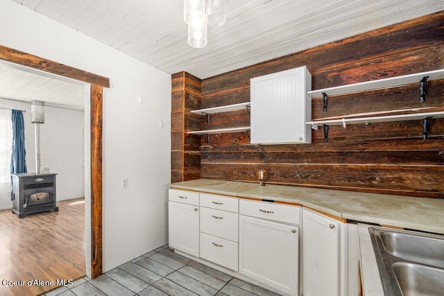 17320 E Perimeter Rd, Athol, ID 83801 - kitchen featuring a wood stove, white cabinetry, light countertops, and wood walls