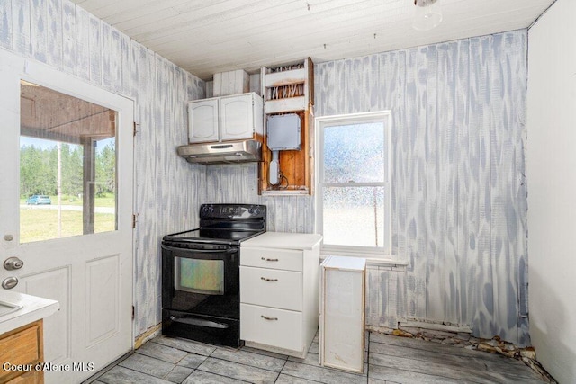 17320 E Perimeter Rd, Athol, ID 83801 - kitchen with black range with electric cooktop, under cabinet range hood, white cabinets, wallpapered walls, and light countertops