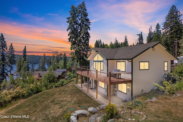 17544 E Arapaho Rd, Bayview, ID 83803 - back of property at dusk with a deck, a yard, a patio, and roof with shingles