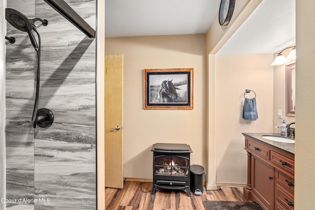17544 E Arapaho Rd, Bayview, ID 83803 - full bathroom with a wood stove, vanity, wood finished floors, and a shower