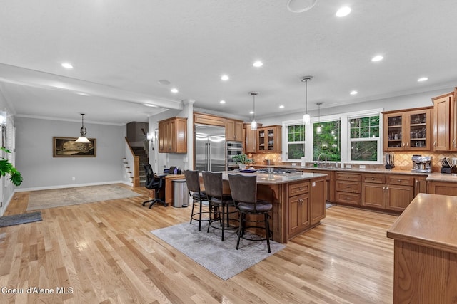 12155 N Yearling Cir, Hayden, ID 83835 - kitchen featuring brown cabinets, appliances with stainless steel finishes, backsplash, a center island, and a kitchen bar