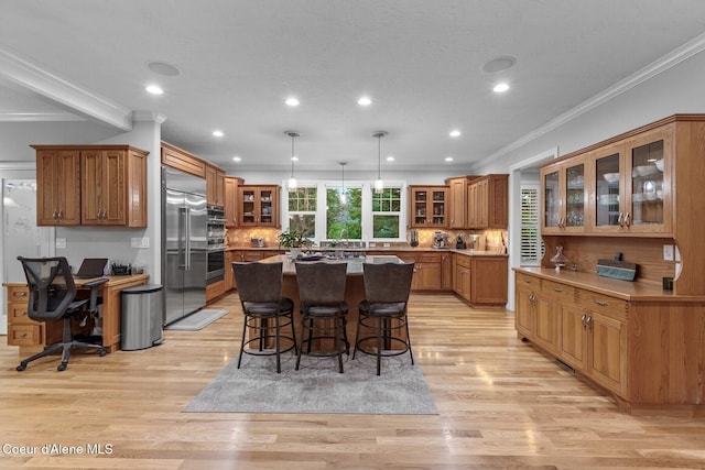 12155 N Yearling Cir, Hayden, ID 83835 - kitchen with a center island, a kitchen bar, brown cabinets, appliances with stainless steel finishes, and ornamental molding