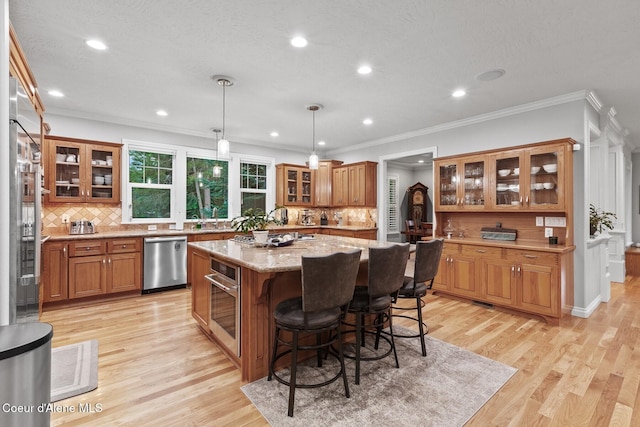 12155 N Yearling Cir, Hayden, ID 83835 - kitchen featuring dishwasher, brown cabinetry, a center island, tasteful backsplash, and ornamental molding