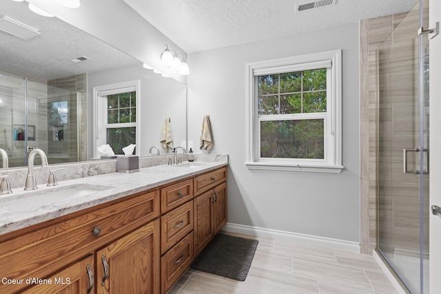 12155 N Yearling Cir, Hayden, ID 83835 - full bathroom with a textured ceiling, double vanity, healthy amount of natural light, a shower stall, and tile patterned flooring
