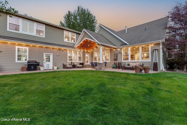 12155 N Yearling Cir, Hayden, ID 83835 - back of property at dusk with an outdoor living space, a patio, a yard, and roof with shingles