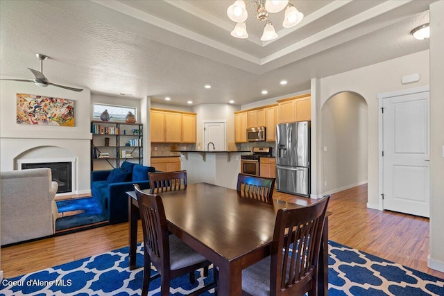 1232 W Grove Way, Coeur Dalene, ID 83815 - dining room featuring a chandelier, arched walkways, light wood-type flooring, recessed lighting, and a glass covered fireplace