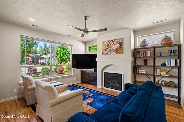 1232 W Grove Way, Coeur Dalene, ID 83815 - living area featuring wood finished floors, ceiling fan, a glass covered fireplace, and a textured ceiling