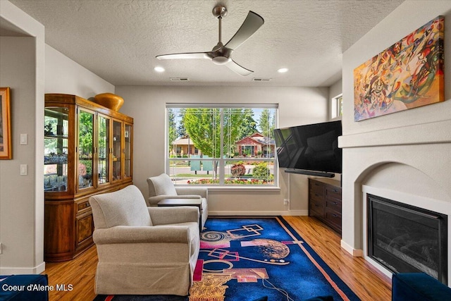 1232 W Grove Way, Coeur Dalene, ID 83815 - living area with wood finished floors, a glass covered fireplace, ceiling fan, a textured ceiling, and recessed lighting