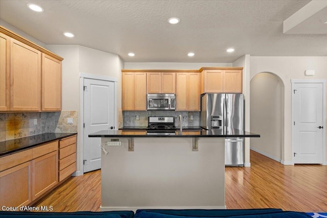 1232 W Grove Way, Coeur Dalene, ID 83815 - kitchen featuring appliances with stainless steel finishes, light wood-style flooring, dark countertops, a breakfast bar area, and recessed lighting