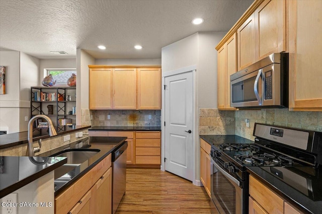 1232 W Grove Way, Coeur Dalene, ID 83815 - kitchen with stainless steel appliances, a textured ceiling, dark countertops, light brown cabinetry, and light wood-style flooring