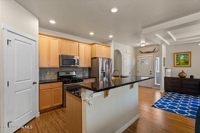1232 W Grove Way, Coeur Dalene, ID 83815 - kitchen with appliances with stainless steel finishes, light wood finished floors, arched walkways, dark countertops, and a textured ceiling