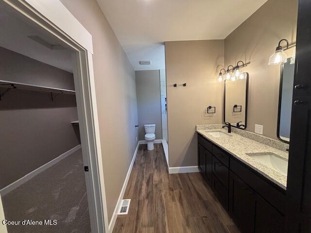 32926 N 10th Ave, Spirit Lake, ID 83869 - bathroom featuring double vanity, a walk in closet, and wood finished floors