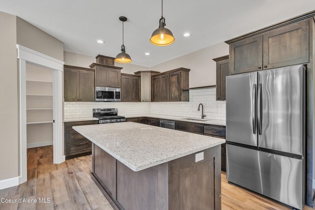 32926 N 10th Ave, Spirit Lake, ID 83869 - kitchen featuring appliances with stainless steel finishes, dark brown cabinetry, a kitchen island, decorative backsplash, and pendant lighting