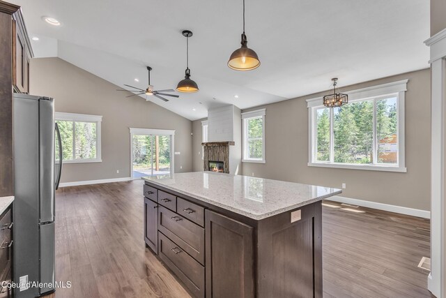 32926 N 10th Ave, Spirit Lake, ID 83869 - kitchen featuring freestanding refrigerator, a glass covered fireplace, dark brown cabinets, a ceiling fan, and vaulted ceiling