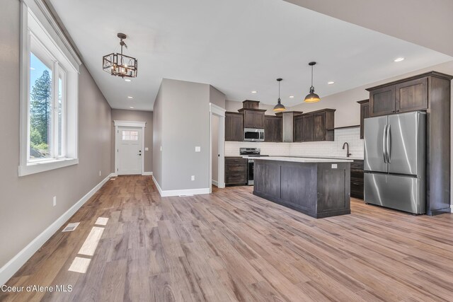 32926 N 10th Ave, Spirit Lake, ID 83869 - kitchen featuring appliances with stainless steel finishes, dark brown cabinetry, tasteful backsplash, light countertops, and light wood-style floors