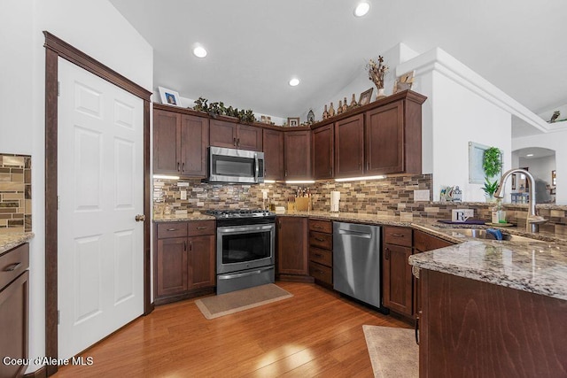 6487 W Covenant St, Rathdrum, ID 83858 - kitchen featuring stainless steel appliances, backsplash, light wood-style floors, light stone counters, and arched walkways