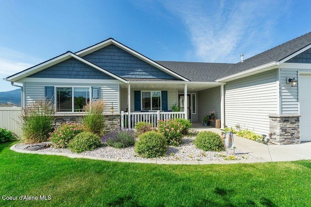 6487 W Covenant St, Rathdrum, ID 83858 - view of front of house featuring covered porch, a garage, a front yard, stone siding, and roof with shingles
