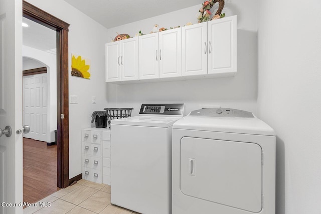 6487 W Covenant St, Rathdrum, ID 83858 - laundry room featuring independent washer and dryer, cabinet space, arched walkways, and light tile patterned floors