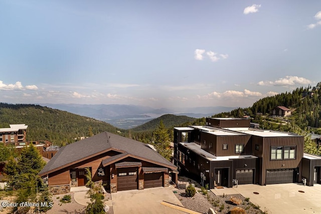 98 Chutes Ln, Sandpoint, ID 83864 - view of front of house featuring a mountain view, concrete driveway, stone siding, and a garage