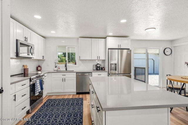 320 E Dakota Ave, Hayden, ID 83835 - kitchen featuring stainless steel appliances, light wood-type flooring, decorative backsplash, a textured ceiling, and a center island