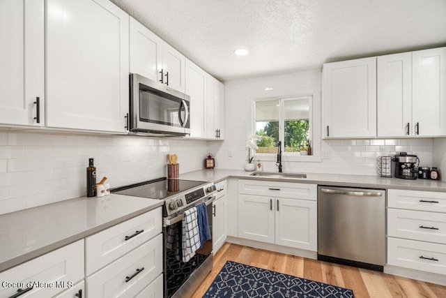 320 E Dakota Ave, Hayden, ID 83835 - kitchen with stainless steel appliances, tasteful backsplash, light countertops, white cabinetry, and light wood-style flooring