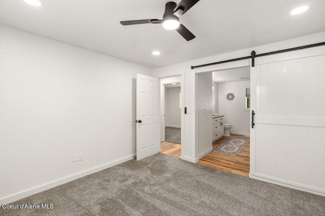 320 E Dakota Ave, Hayden, ID 83835 - unfurnished bedroom featuring a barn door, carpet floors, recessed lighting, ensuite bath, and ceiling fan
