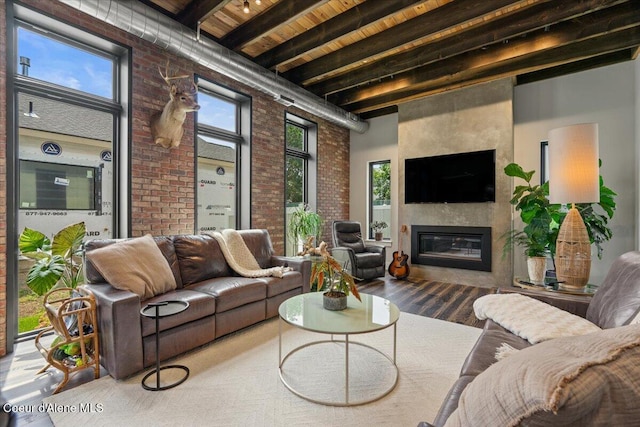9137 N Raintree Ln, Hayden, ID 83835 - living room featuring brick wall, wood finished floors, a wooden ceiling with exposed beams, a glass covered fireplace, and a high ceiling