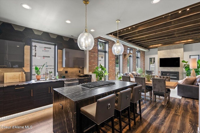 9137 N Raintree Ln, Hayden, ID 83835 - kitchen with dark wood-style floors, appliances with stainless steel finishes, a kitchen bar, open floor plan, and a large fireplace