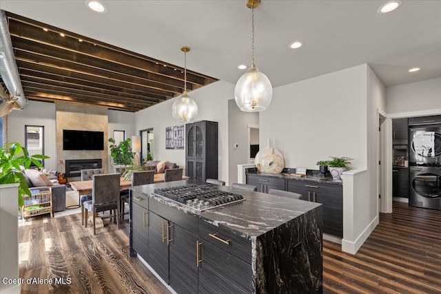 9137 N Raintree Ln, Hayden, ID 83835 - kitchen featuring stainless steel gas stovetop, dark cabinetry, stacked washer / dryer, dark wood-type flooring, and a large fireplace