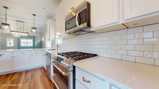 1121 E Indiana Ave, Coeur Dalene, ID 83814 - kitchen with appliances with stainless steel finishes, white cabinets, backsplash, and pendant lighting
