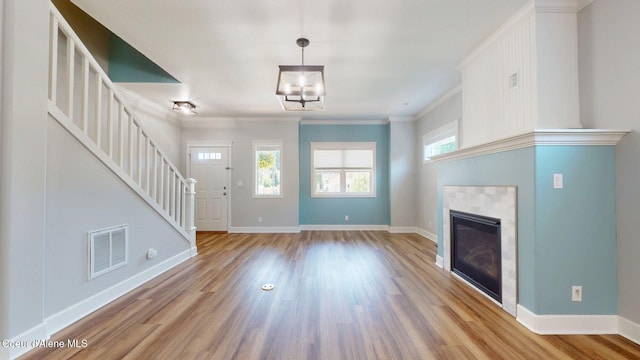 1121 E Indiana Ave, Coeur Dalene, ID 83814 - unfurnished living room featuring stairs, wood finished floors, a tiled fireplace, and crown molding