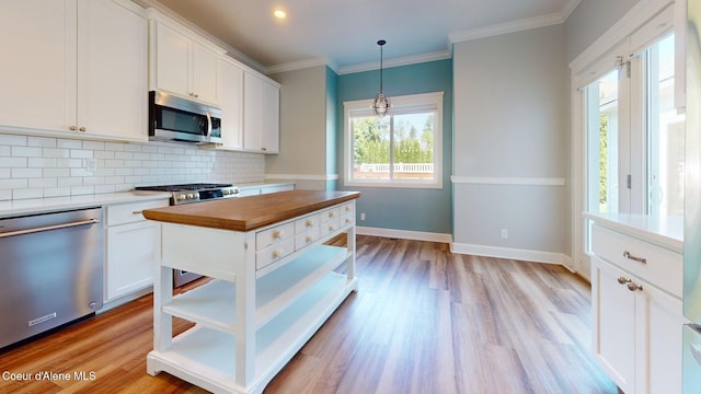 1121 E Indiana Ave, Coeur Dalene, ID 83814 - kitchen with appliances with stainless steel finishes, decorative backsplash, white cabinetry, light wood-style floors, and decorative light fixtures