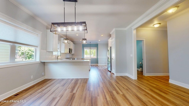 1121 E Indiana Ave, Coeur Dalene, ID 83814 - kitchen with light countertops, appliances with stainless steel finishes, white cabinetry, light wood-style flooring, and a peninsula