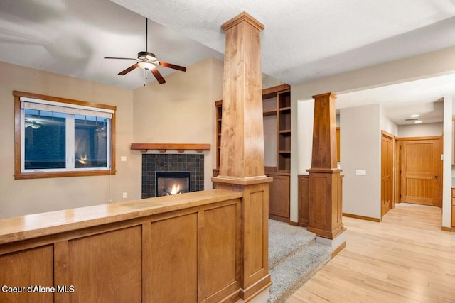 2848 N O Connor Blvd, Post Falls, ID 83854 - unfurnished living room featuring light wood-type flooring, ceiling fan, a tiled fireplace, decorative columns, and lofted ceiling