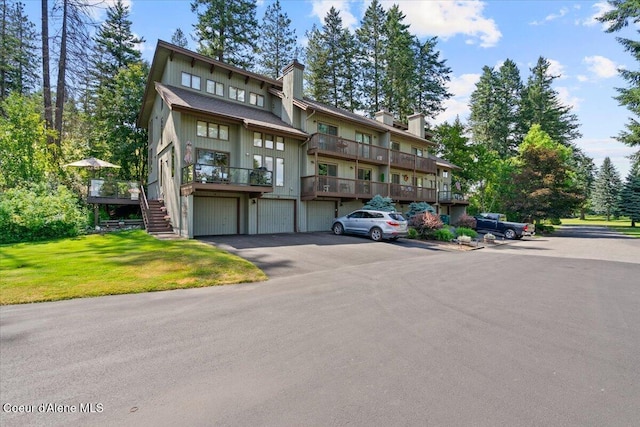 5276 W Racquet Rd Unit 9, Rathdrum, ID 83858 - view of front facade featuring a chimney, stairway, a front lawn, and a garage