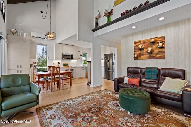 5276 W Racquet Rd Unit 9, Rathdrum, ID 83858 - living room featuring a wall mounted AC, light wood-type flooring, a towering ceiling, and recessed lighting