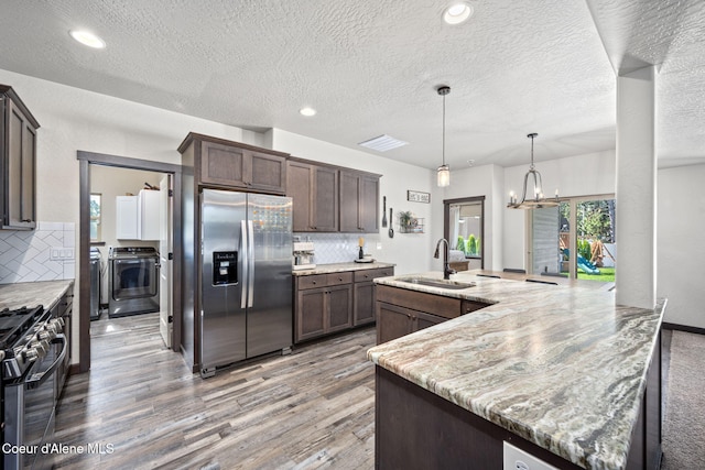 2499 N N Side Saddle Ln, Post Falls, ID 83854 - kitchen with stainless steel appliances, light wood-style flooring, separate washer and dryer, backsplash, and recessed lighting