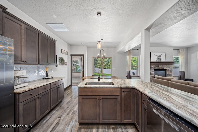 2499 N N Side Saddle Ln, Post Falls, ID 83854 - kitchen featuring stainless steel appliances, open floor plan, a stone fireplace, dark brown cabinetry, and a textured ceiling