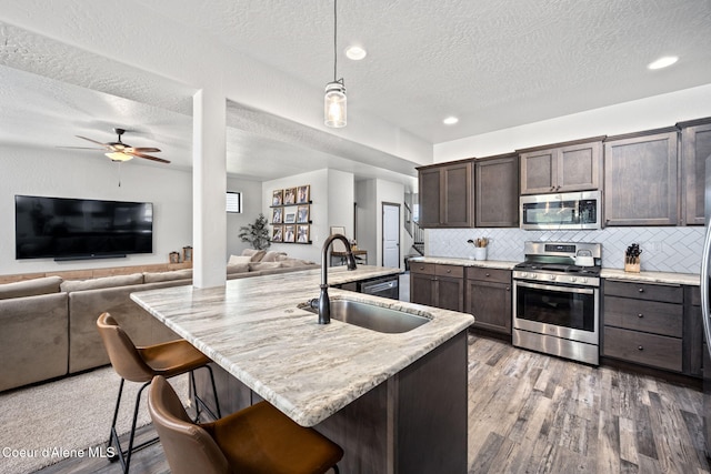 2499 N N Side Saddle Ln, Post Falls, ID 83854 - kitchen with appliances with stainless steel finishes, open floor plan, dark brown cabinets, a textured ceiling, and ceiling fan